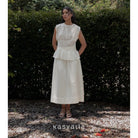 Woman wearing a white dress standing in front of greenery with 'kasyalia' branding.