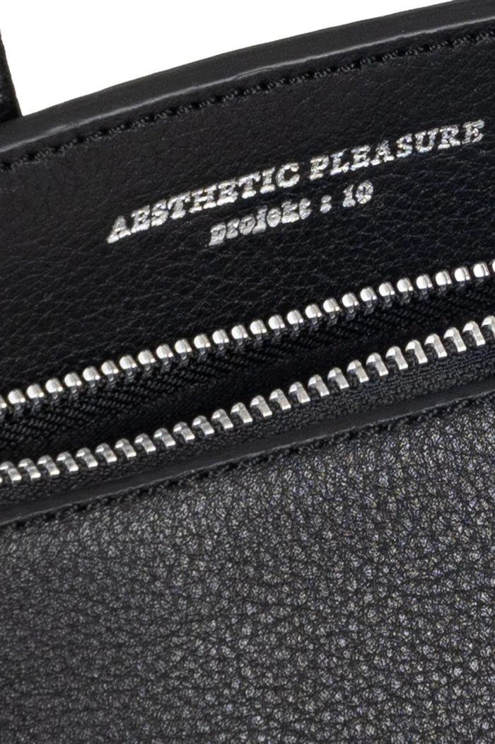Black grain leather bag with silver zipper and 'Aesthetic Pleasure' text on a white background