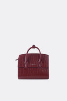 A mini-sized maroon leather handbag with a textured alligator pattern, featuring a detachable strap and silver-tone hardware by Aesthetic Pleasure.