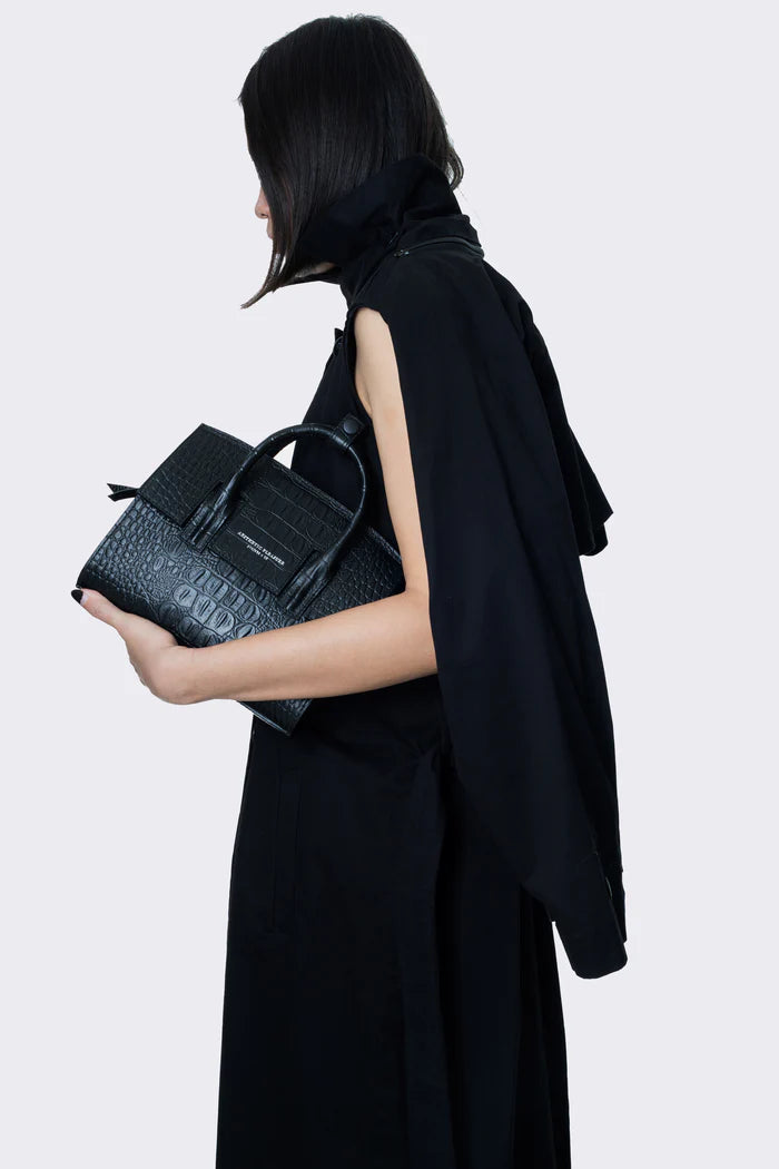 Woman holding a Mini Isolation Bag Croc Black by Aesthetic Pleasure against a light background