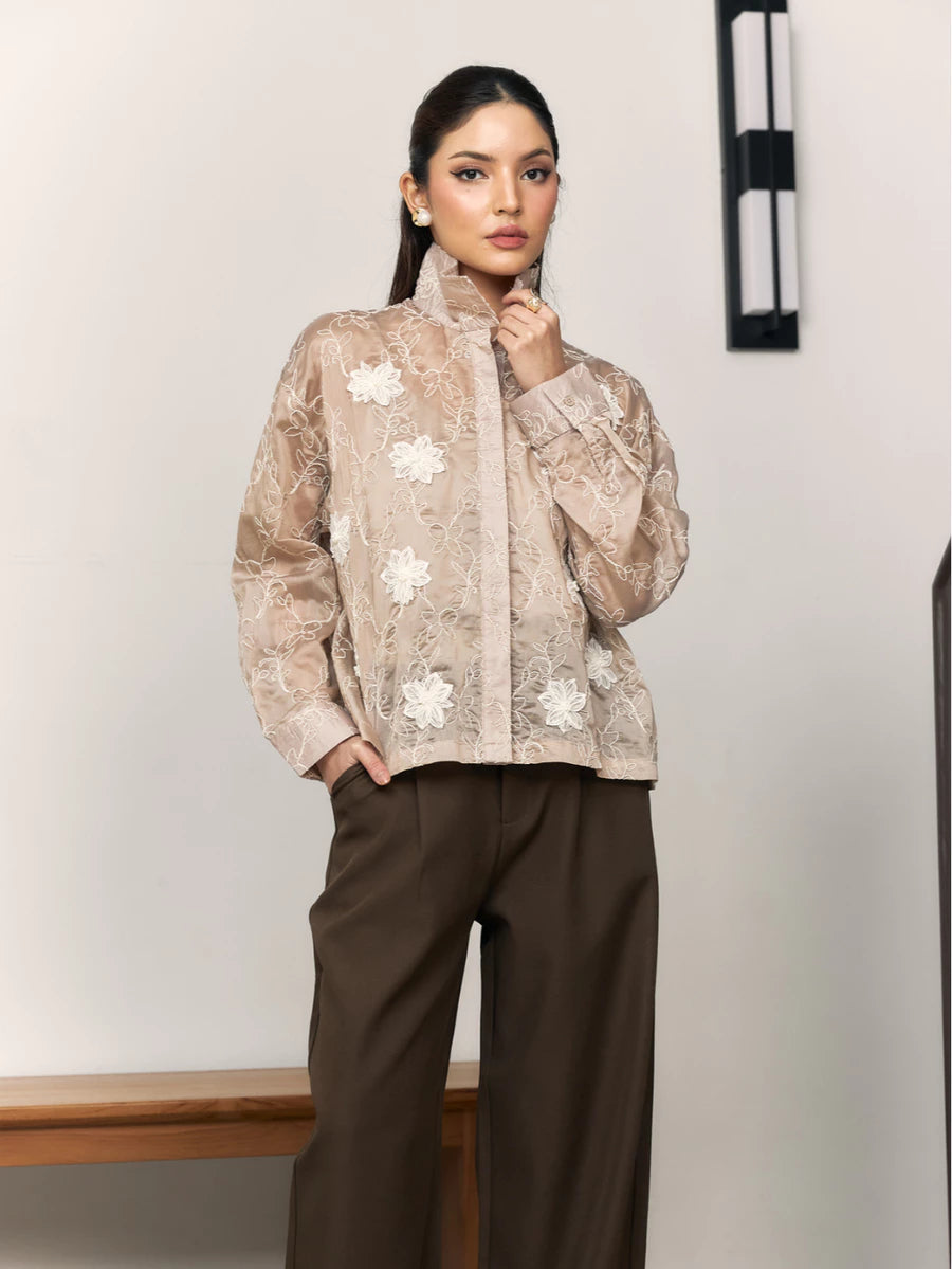 Woman wearing a brown floral shirt  by Studio Tui and brown pants against a plain background