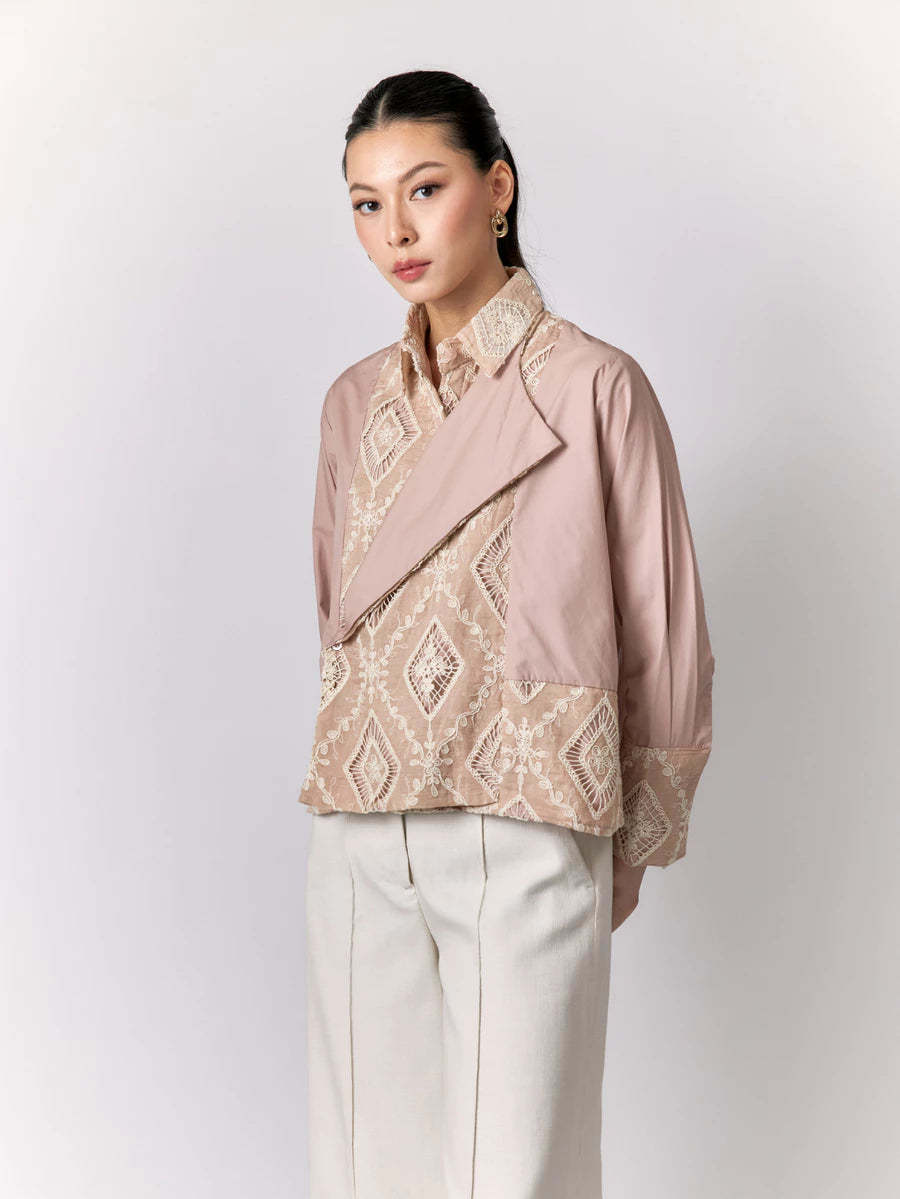 Woman wearing a pink shirt by Studio Tui with intricate patterns on a white background