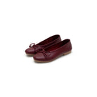 Pair of maroon flat shoes by Cajsa with a bow on a white background