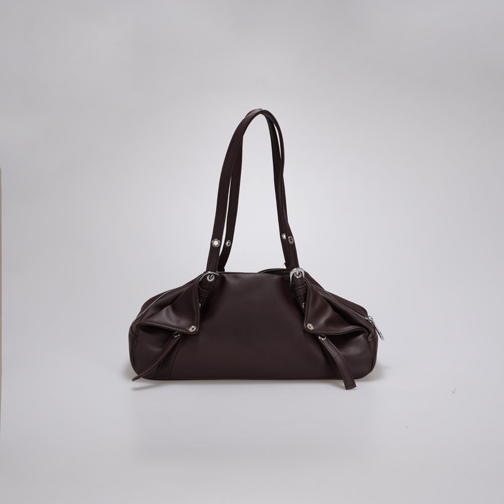 A dark brown leather shoulder bag by Cekhas with a slouchy, rounded silhouette, dual shoulder straps, and silver-tone hardware, photographed against a neutral light gray background.