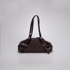 A dark brown leather shoulder bag by Cekhas with a slouchy, rounded silhouette, dual shoulder straps, and silver-tone hardware, photographed against a neutral light gray background.