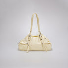 A cream-colored leather shoulder bag by Cekhas with a curved top handle, decorative buckle straps, and silver-tone hardware, shown against a neutral light gray background.