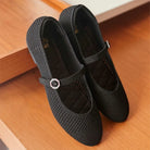 Pair of black mesh flatshoes with a strap by Tutu Toe on a wooden floor