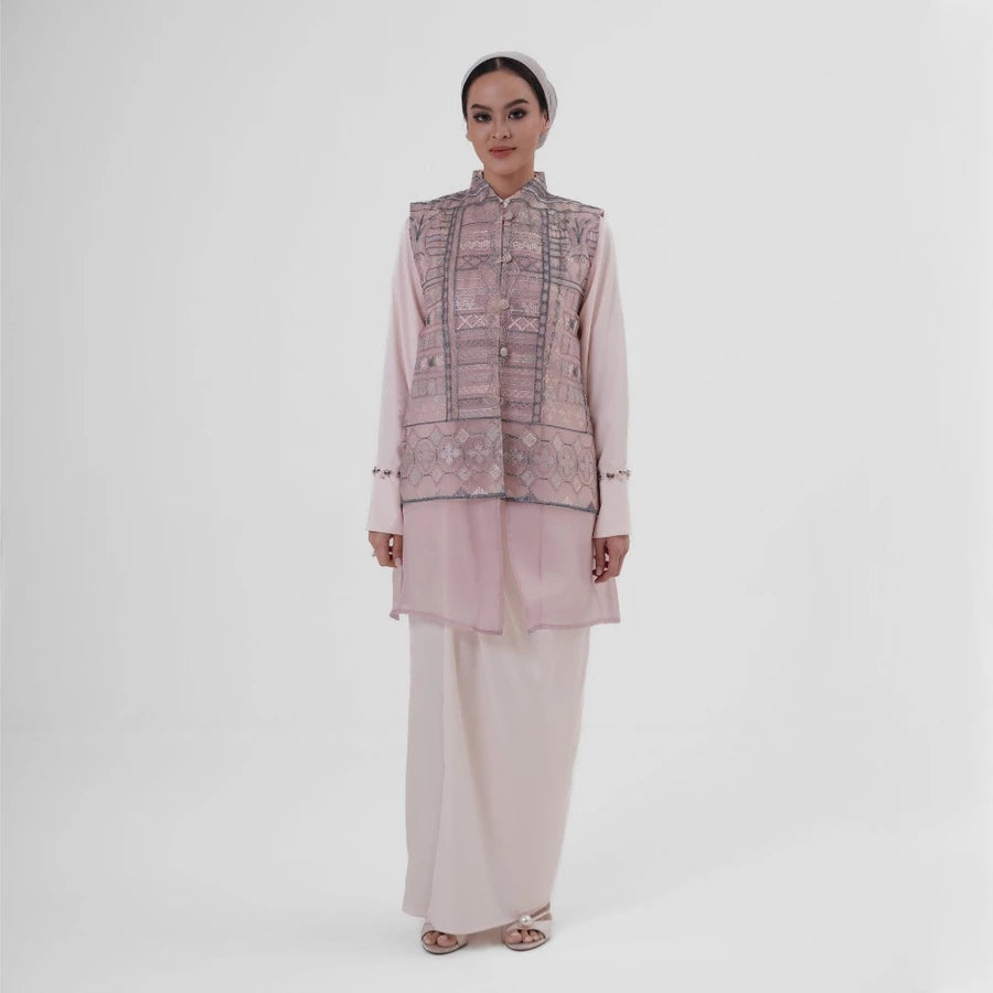Woman wearing a pink tunic by Jenna & Kaia with long skirt on a white background