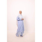 A woman wearing a blue striped tunic with long sleeves and a round neckline, paired with matching pants and a headscarf.