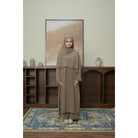 Woman in a beige outfit set by Tubita standing in a room with wooden shelves and a framed picture on the wall.