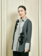 Woman wearing a stylish blue and grey shirt by Studio Tui with floral details against a neutral background