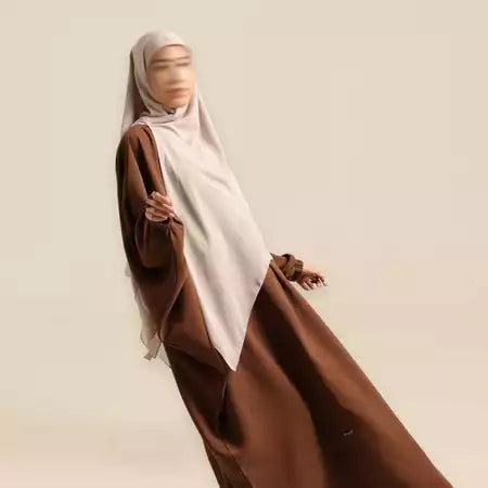 Person wearing a brown dressand beige long hijab by Nehhat Modest on a plain background