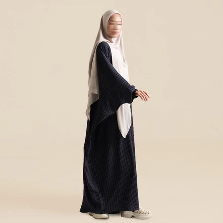 Person wearing abaya by Nehhat Modest with a white hijab on a beige background