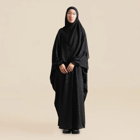 Person wearing a black abaya by Nehhat Modest on a beige background