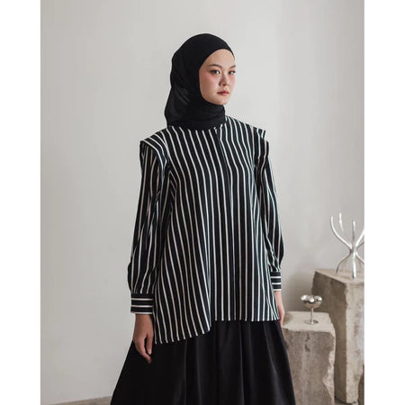 Person wearing a black and white striped shirt by Maima with a hijab in a minimalistic setting