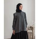 Person wearing a black and white striped shirt by Maima with a hijab in a minimalistic setting
