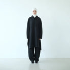 Person wearing a black long hooded sweatshirt by Rashawl with a white headscarf on a white background
