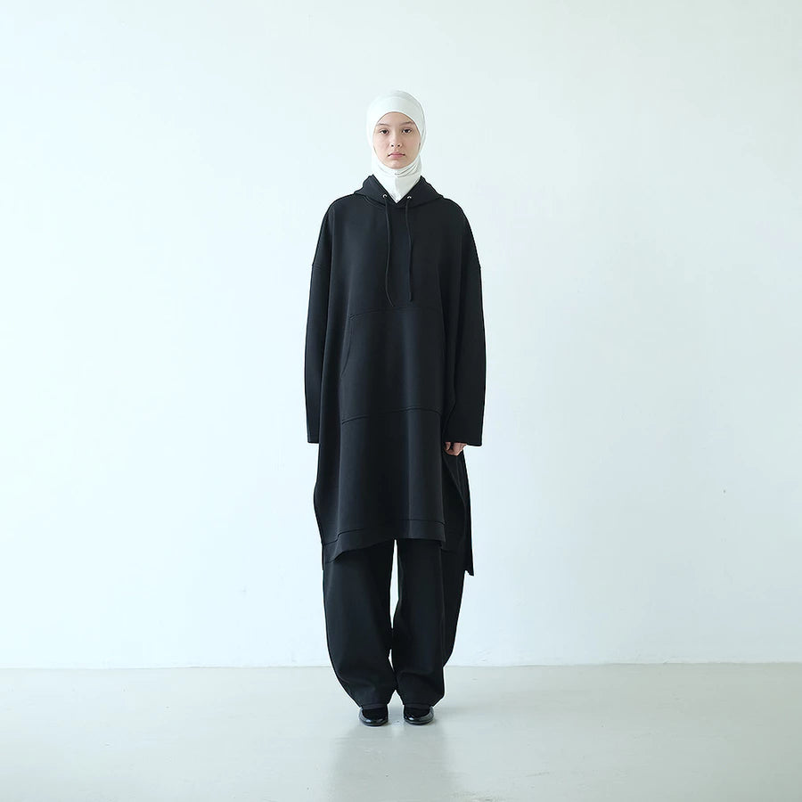 Person wearing a black long hooded sweatshirt by Rashawl with a white headscarf on a white background