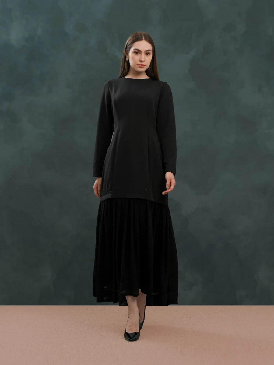 Woman wearing a black dress by Kasa Heritage against a dark green background