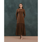 Woman wearing a brown dress by Kasa Heritage against a dark green background