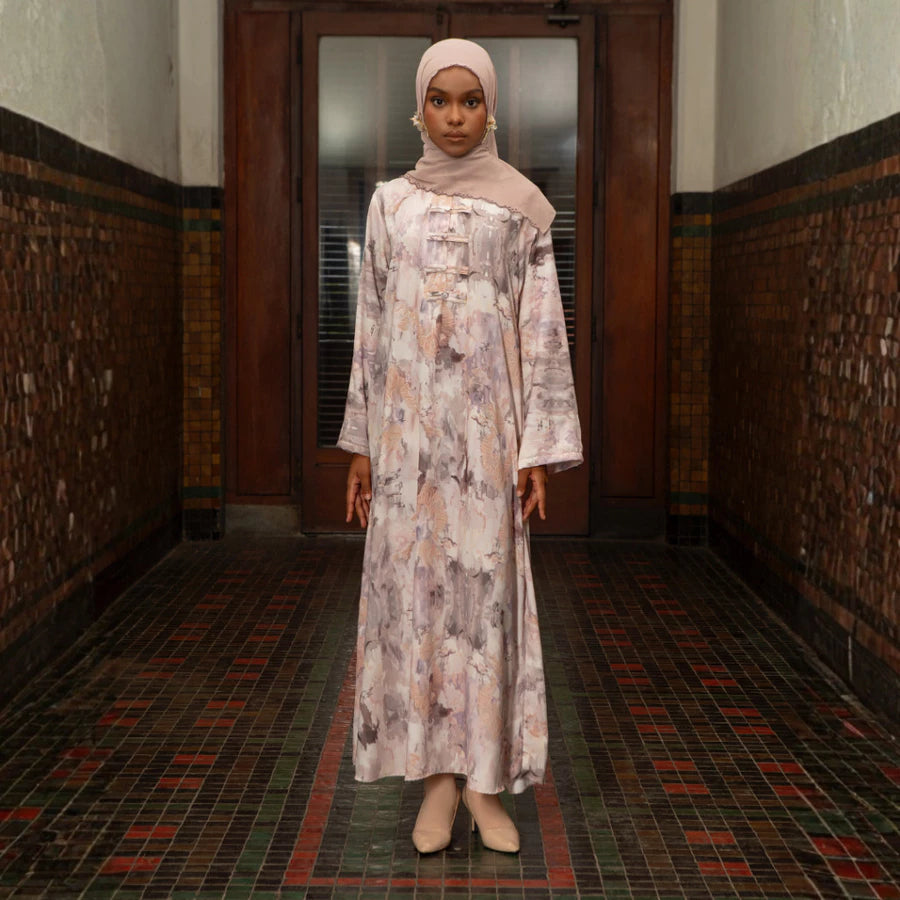 Woman in a floral dress by Lozy Hijab standing in a hallway with patterned walls and floor.