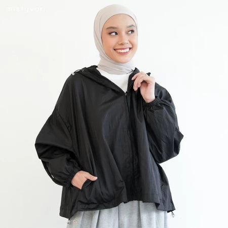 Woman wearing a black jacket by Mistyvori and beige hijab on a white background