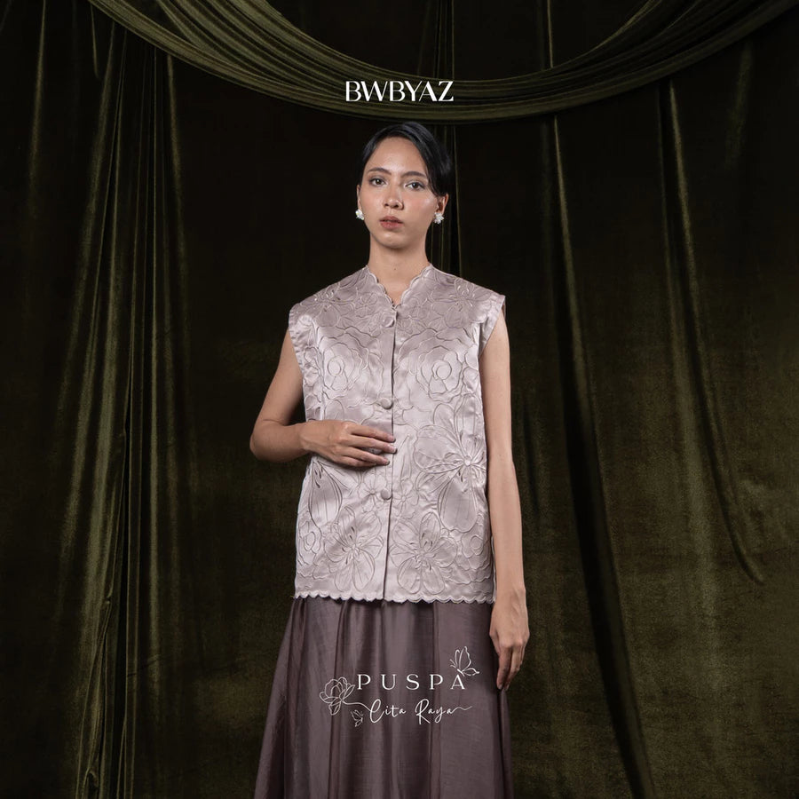 Woman wearing a taupe-colored sleeveless embroidered vest and skirt with 'BWBYAZ' branding.