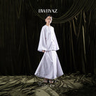 Person wearing a white floral skirt with 'BWBYAZ' branding against a dark curtain background.
