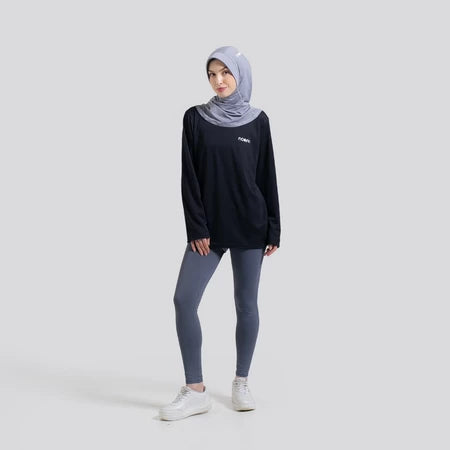 Woman wearing a black long-sleeve top by Noore and gray leggings with a hijab on a white background