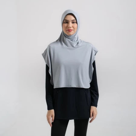 Woman wearing a light gray hijab sport by Noore and black outfit on a white background