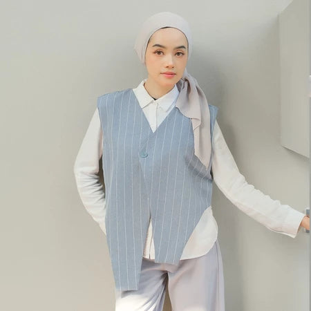 Person wearing a light blue pinstripe vest by Tunique over a white shirt with a plain background