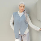 Person wearing a light blue pinstripe vest by Tunique over a white shirt with a plain background