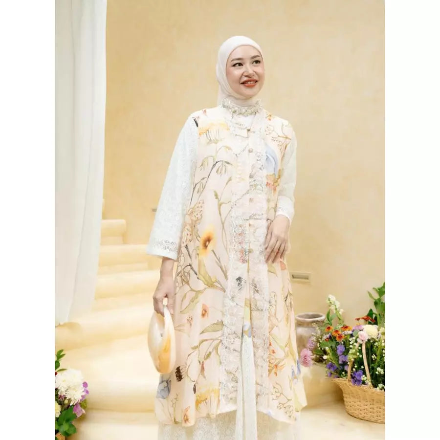 Woman in a floral outfit set by Haidee Orlin standing in a decorated room with flowers and a cake.