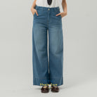 Blue wide-leg jeans from BWBYAZ worn by a person on a gray background.