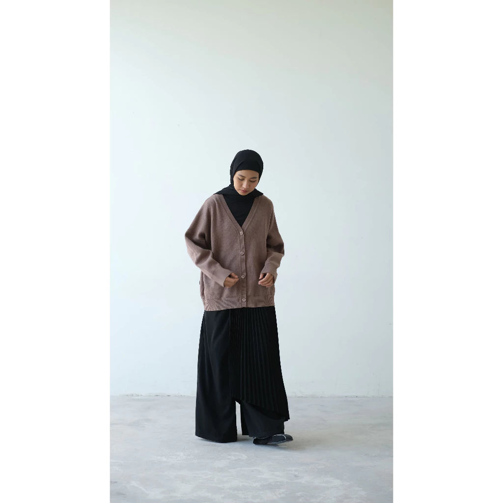 Person wearing a brown cardigan by Rashawl and black skirt against a white background