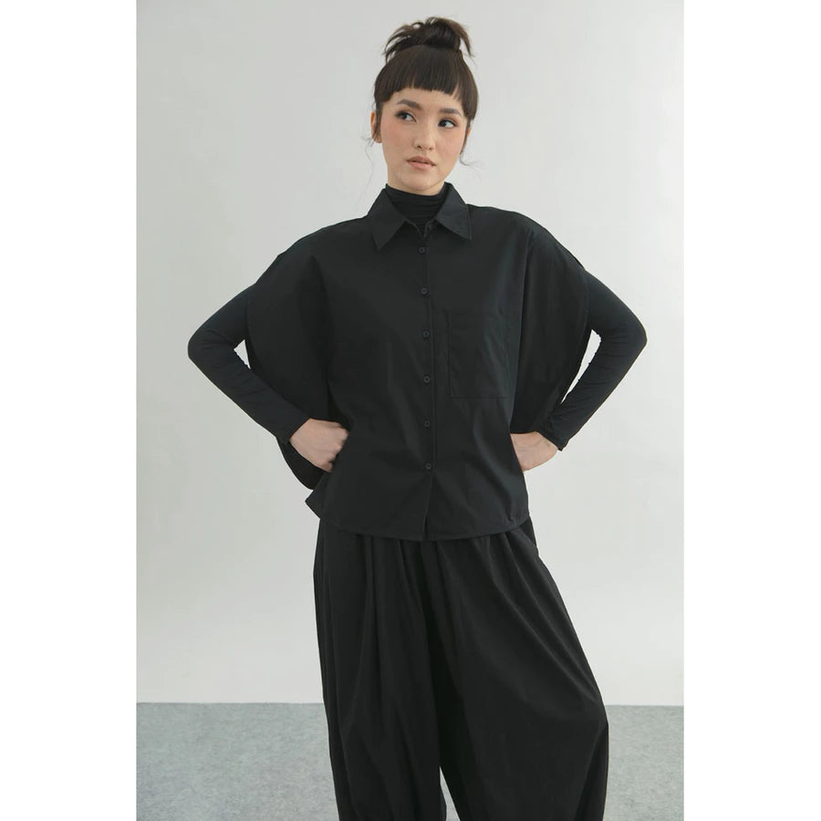 Person wearing a black oversized shirt by Yestoday with a plain background