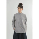 Person wearing a gray long-sleeve boxy shirt by Yestoday with a white background