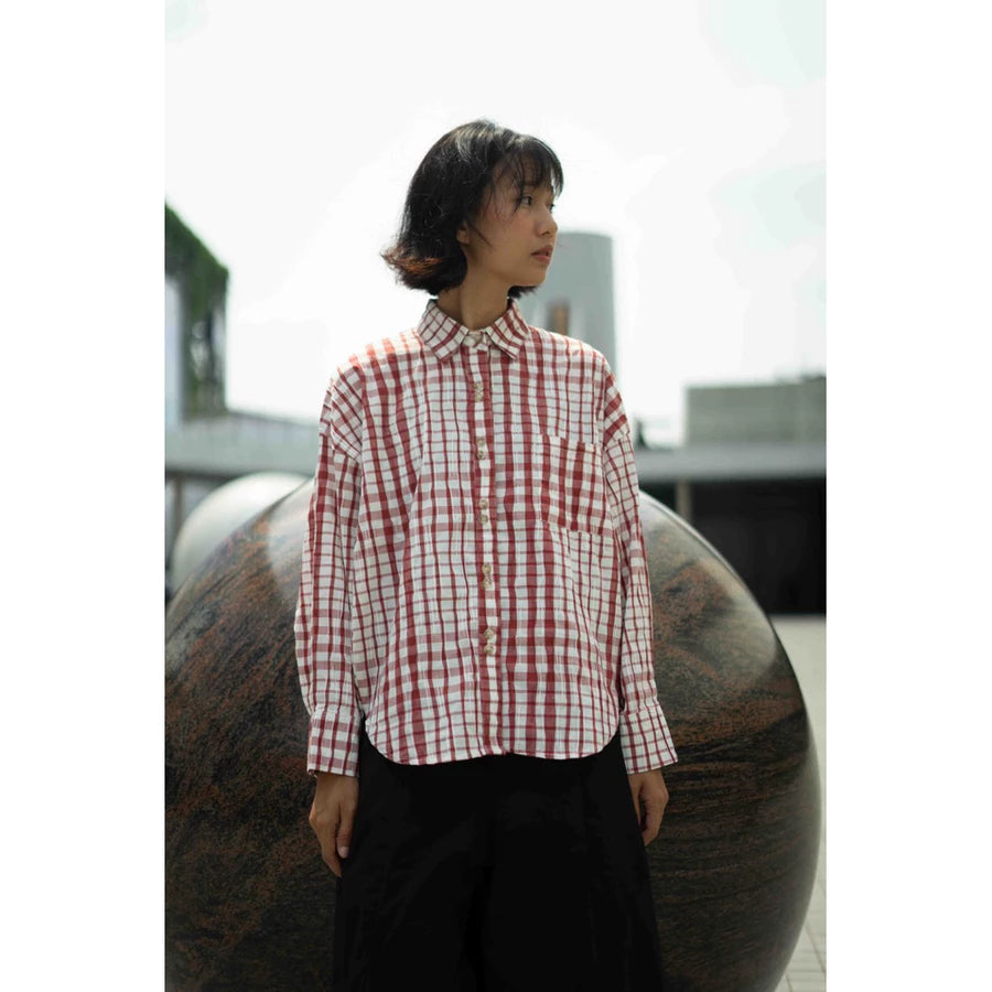 Person wearing a red and white checkered shirt by Yestoday standing in front of a large spherical object.