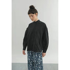Person wearing a black shirt by Yestoday and patterned pants against a plain background