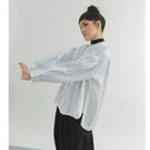 Person wearing a sheer dotted white shirt by Yestoday over a black turtleneck with a plain background