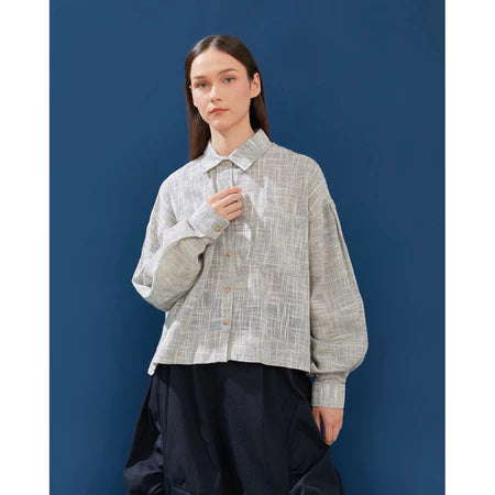 Person wearing a white with black-textured shirt with a dark blue background