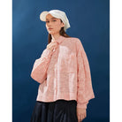 Person wearing a white with pink-textured shirt and white cap against a blue background