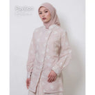 Woman wearing a light pink tunic by Atala Scarves with floral patterns on a white background.

Seorang wanita mengenakan tunik berwarna pink muda dari Atala Scarves dengan motif bunga pada latar belakang putih.
