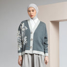 Woman wearing a gray cardigan by Hijabchic with floral embroidery and a hijab against a neutral background