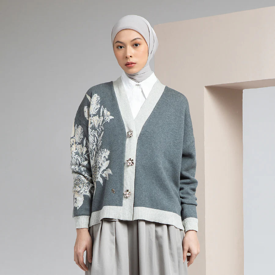 Woman wearing a gray cardigan by Hijabchic with floral embroidery and a hijab against a neutral background