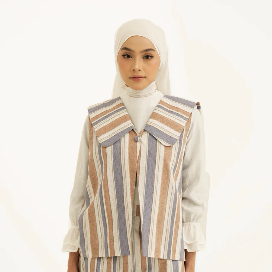 Woman wearing a striped vest by Tunique over white top with a hijab on a white background
