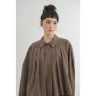Person wearing a brown checkered blouse by Yestoday against a white background