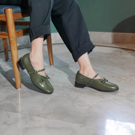 A person wearing green, pointed, flat shoes with a buckle strap across the foot by Dianable.
