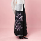 Black skirt with floral pattern worn by a person on a pink background, with 'BWBYAZ' branding.