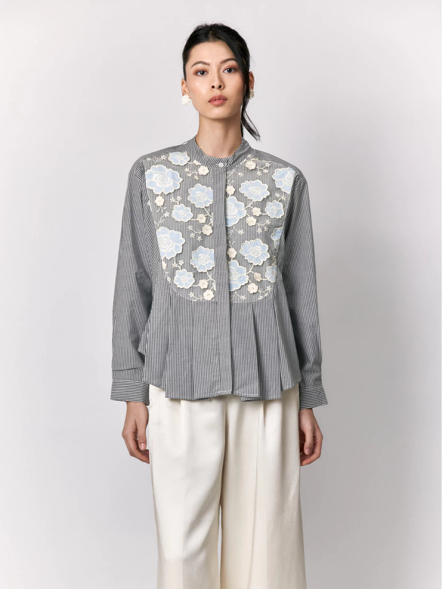 Woman wearing a gray striped shirt by Studio Tui with floral embroidery on a white background
